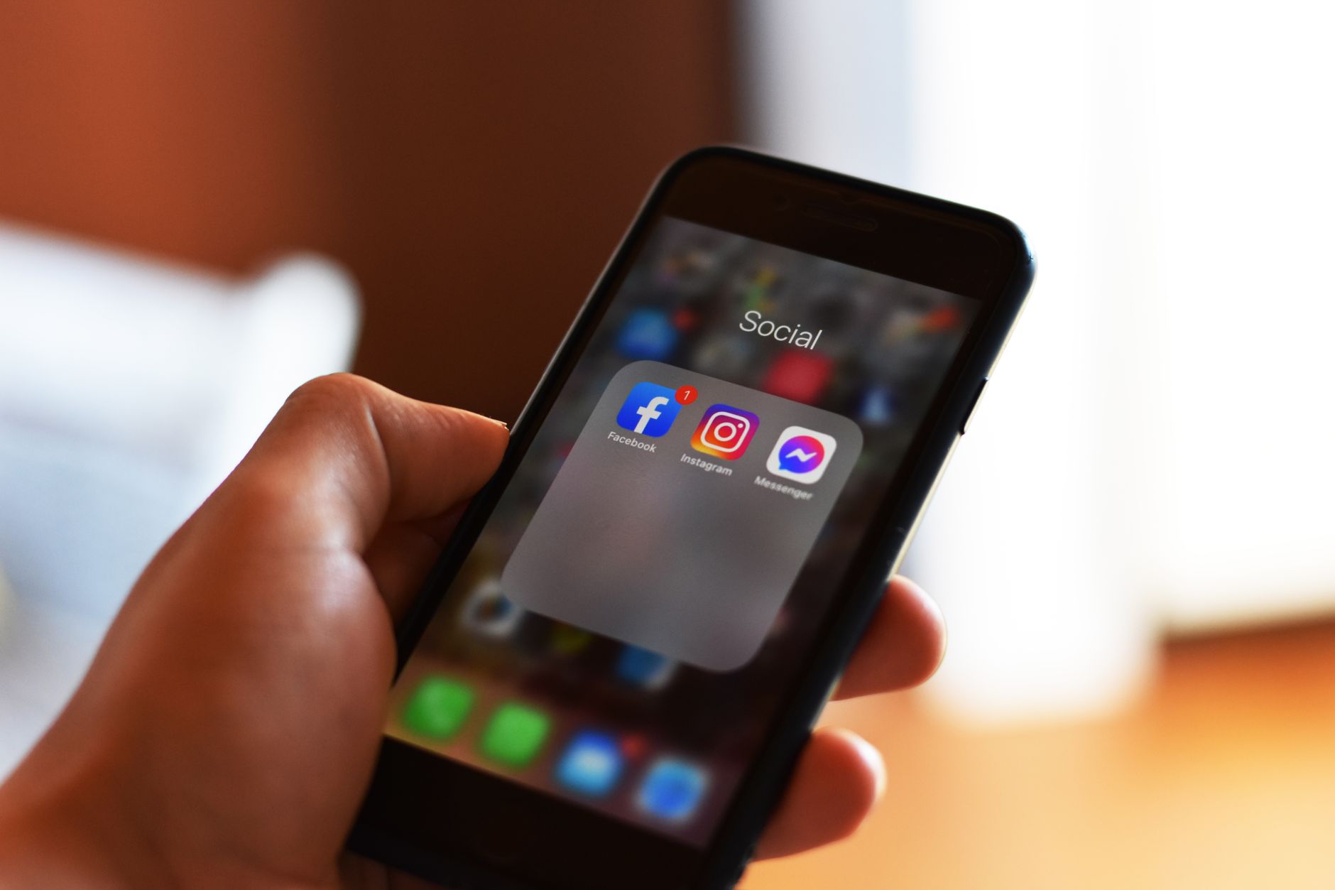 Mão segurando smartphone com aplicativos na tela