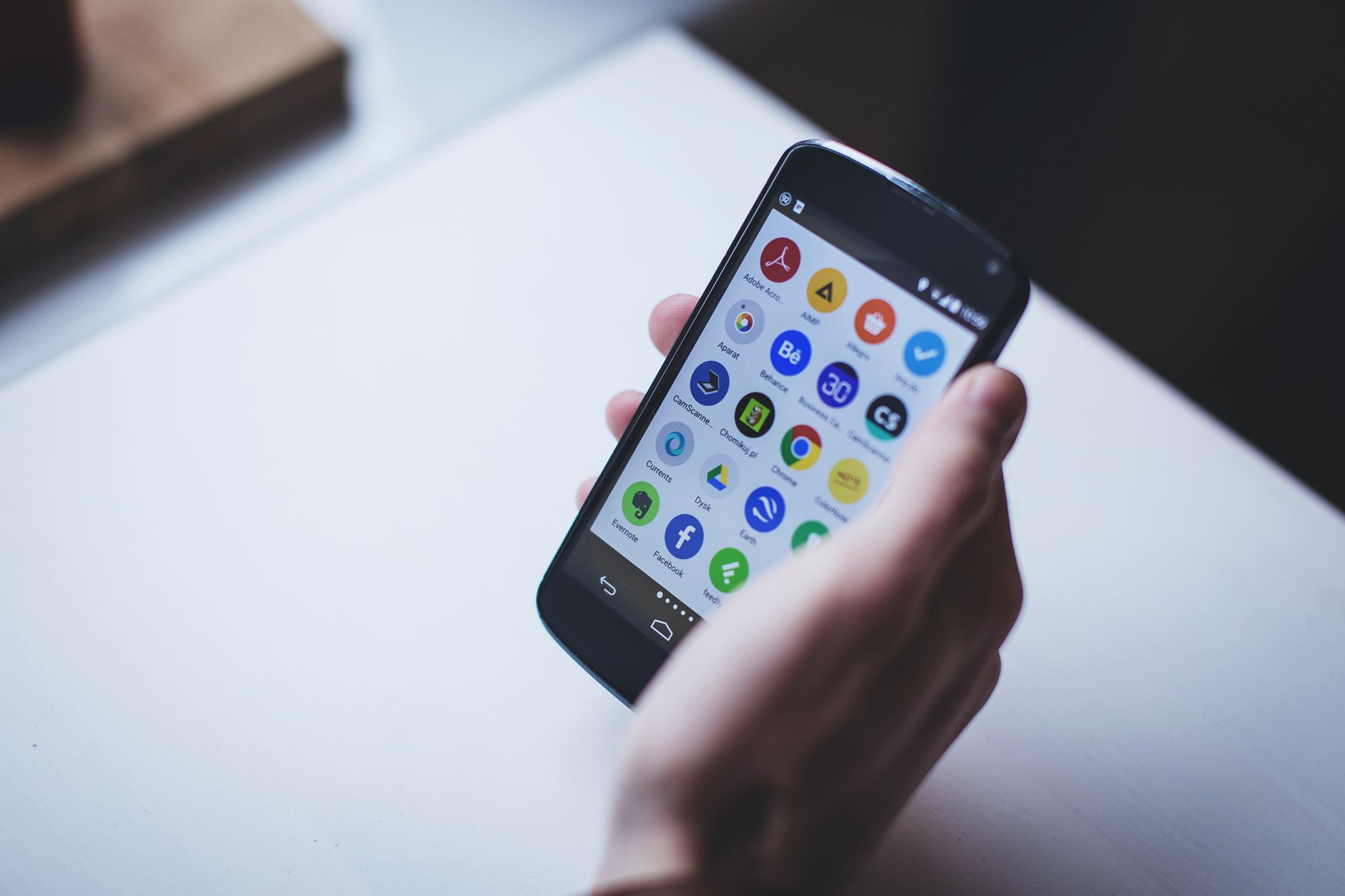 Pessoa segurando um celular com ícones de aplicativos