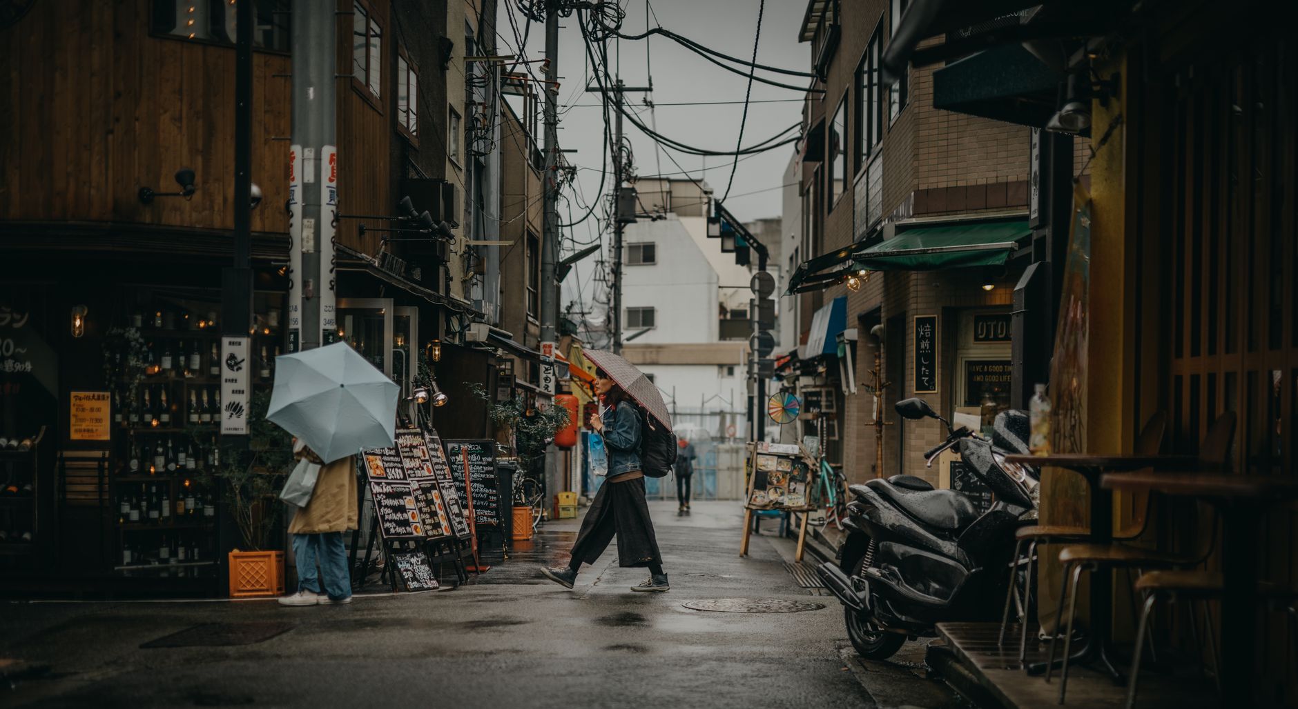 Pedestres com guarda-chuvas em beco movimentado em dia de chuva